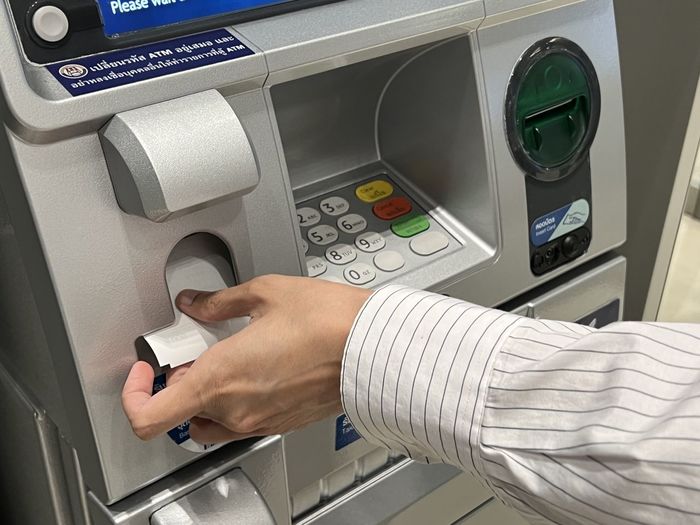 Cropped hand of man using atm