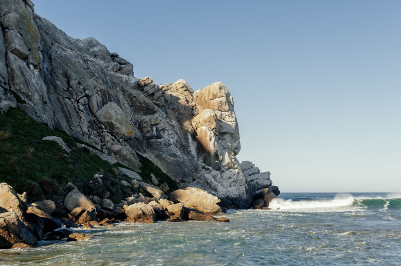 Rock formation on beach against clear sky