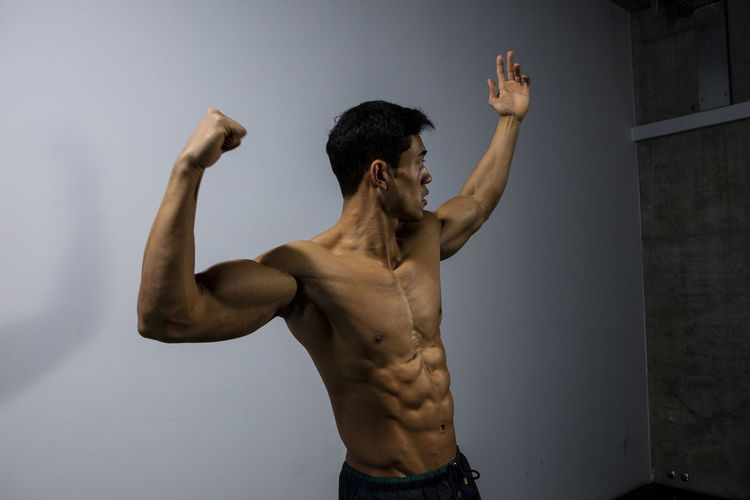 Shirtless muscular man standing against wall