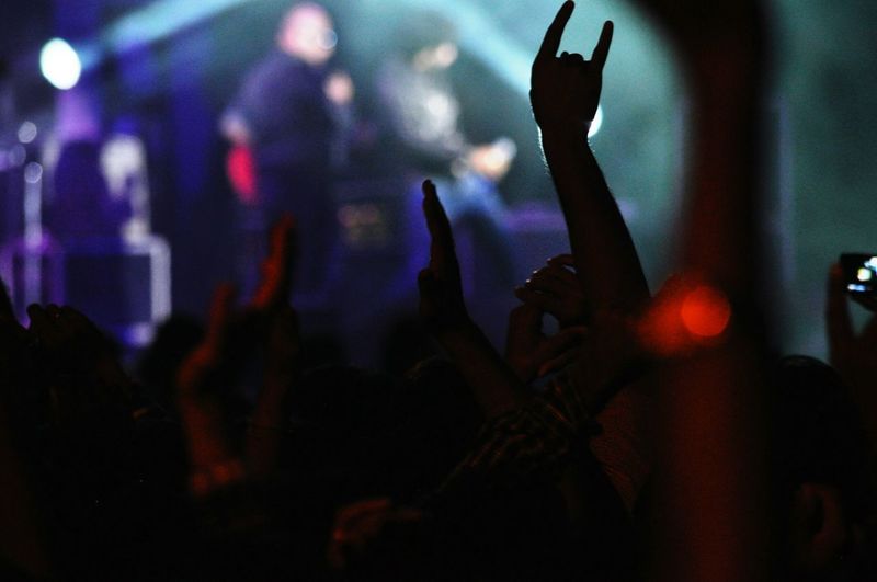 People with dancing with arms raised at concert
