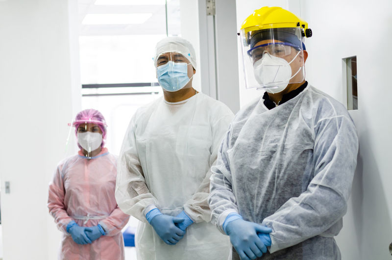 Doctors wearing flu mask and protective suit standing in hospital