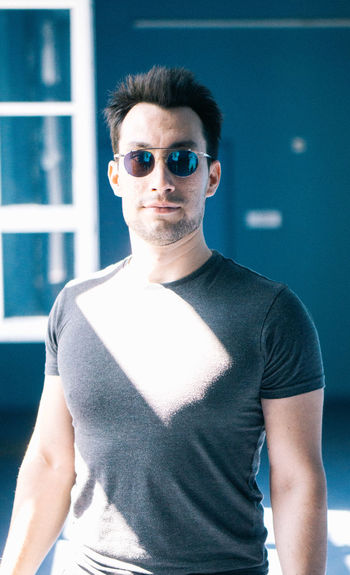 Portrait of man wearing sunglasses while standing against wall