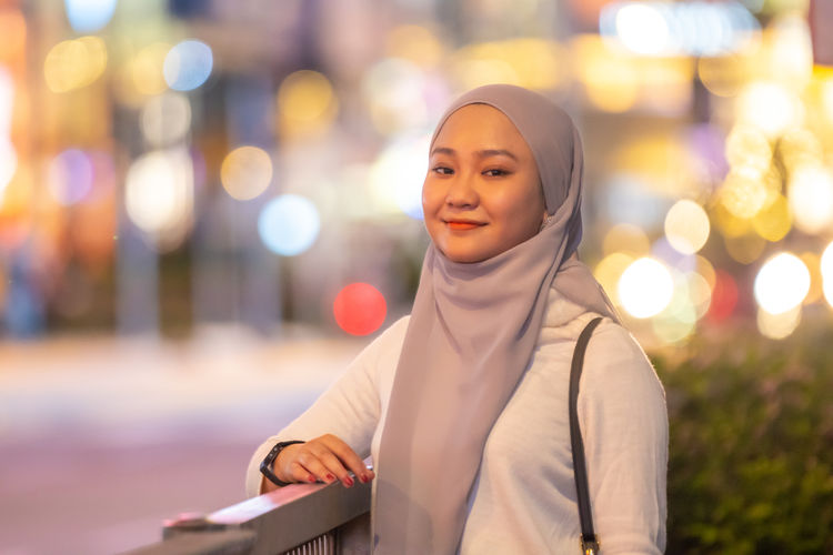 Portrait of smiling young woman wearing hijab standing in city