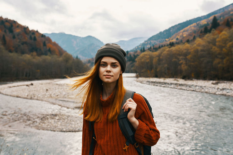 Portrait of beautiful young woman standing against mountain
