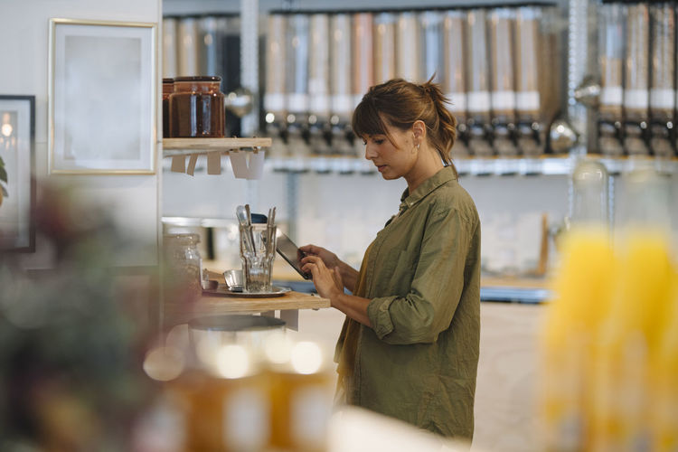 Female entrepreneur using digital tablet while standing coffee shop