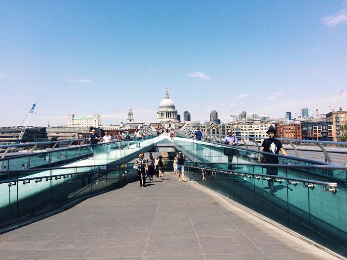 People on london millennium footbridge in city against sky