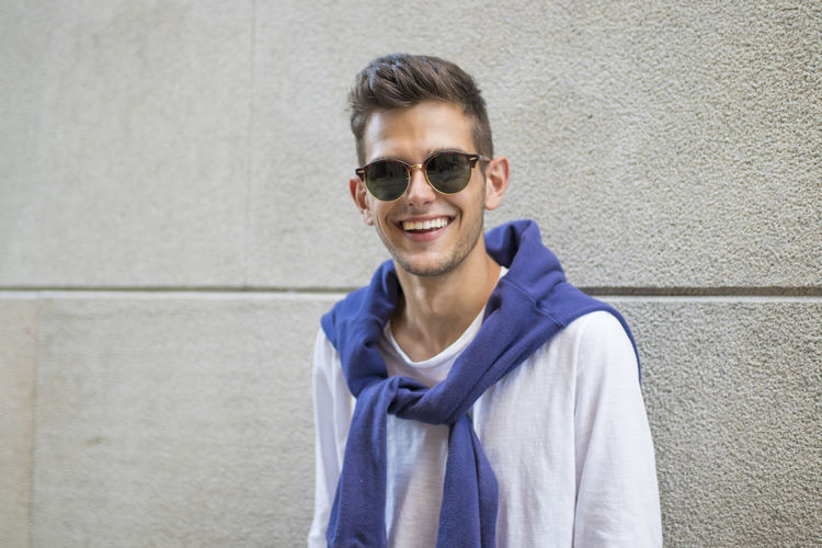 Young woman wearing sunglasses while standing against wall
