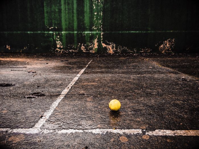 Tennis ball on wet ground against wall