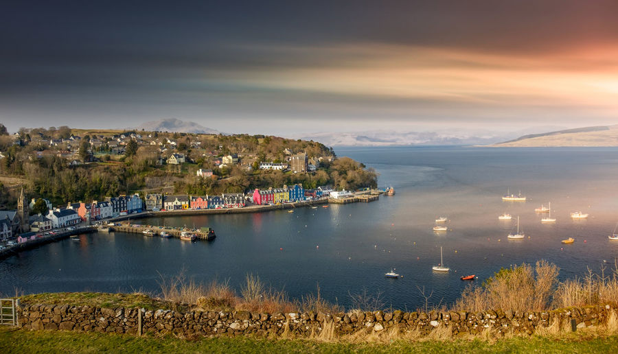 Scenic view of tobermory bay against dramatic sky during sunset