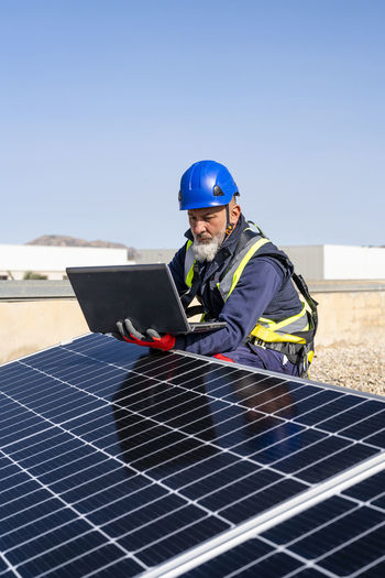 Engineer working on laptop by solar panels