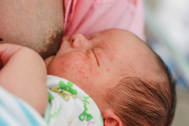 Close-up of woman breastfeeding baby boy at home