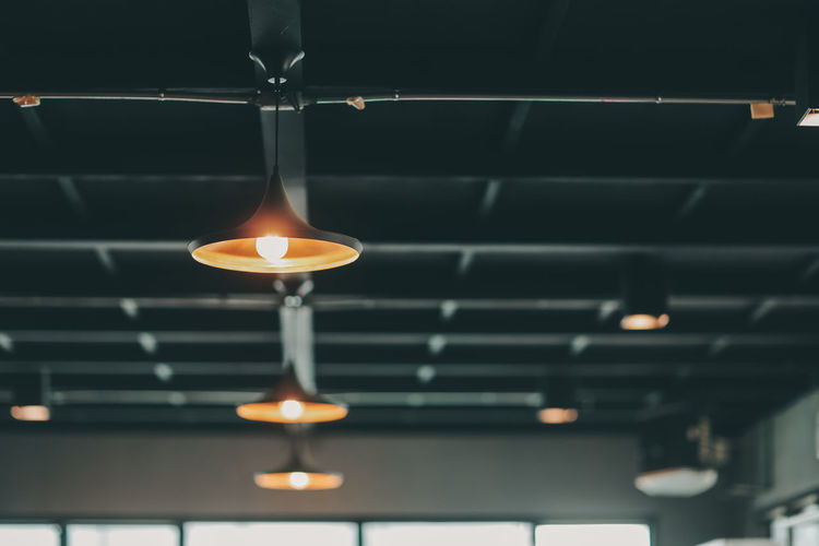 Low angle view of illuminated pendant lights hanging from ceiling