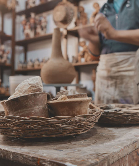 Man molding clay to make ceramics with his hands, artisan working in his workshop, selective focus