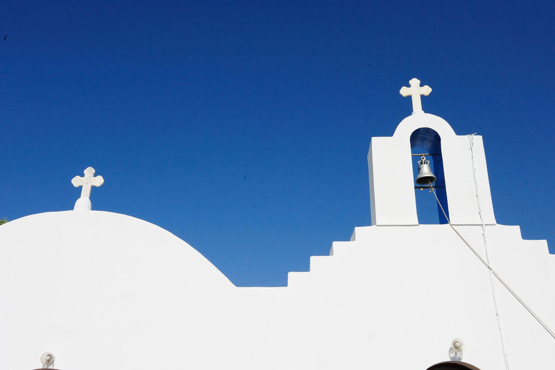 Low angle view of bell tower of church against clear blue sky at santorini