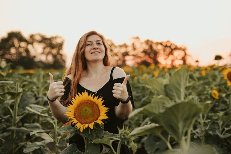 A young woman holds sunflowers.