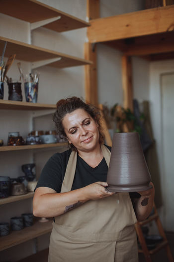 A middle-aged woman makes a vase of clay