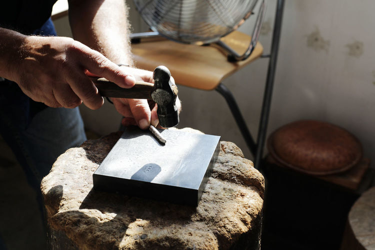Jeweller hammering on metal to make jewelry in workshop