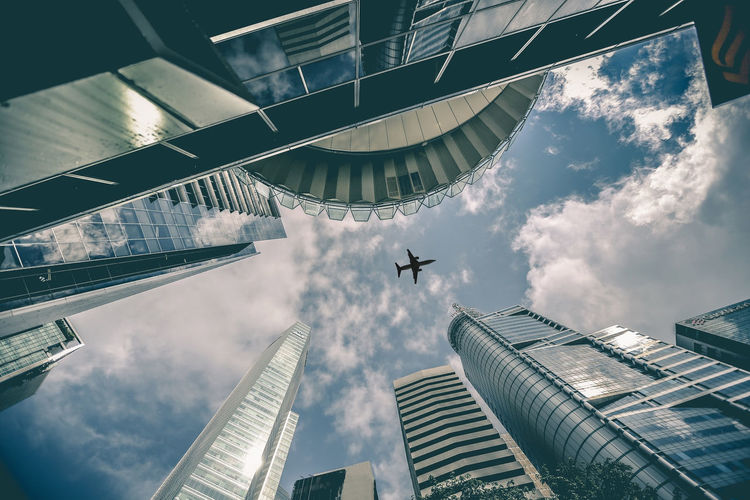 Low angle view of airplane and modern buildings against sky