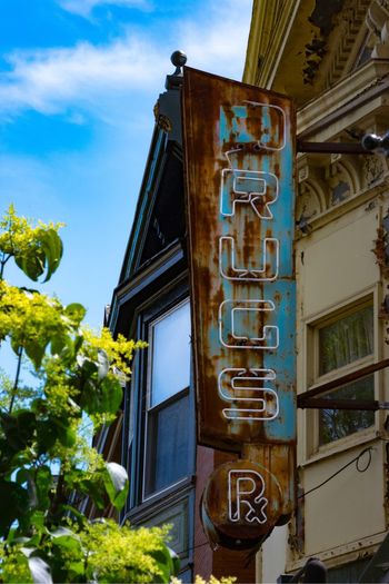 Low angle view of damaged neon store sign on building