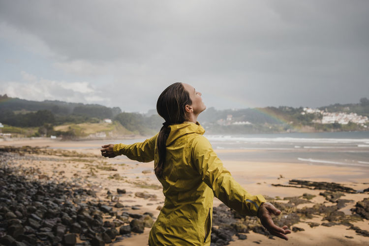 Smiling woman in raincoat at beach during rainy season