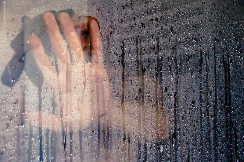 Close-up of cropped hand on wet glass