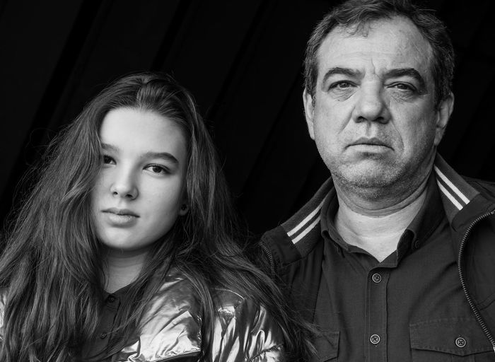 Portrait of mature man with daughter against black background