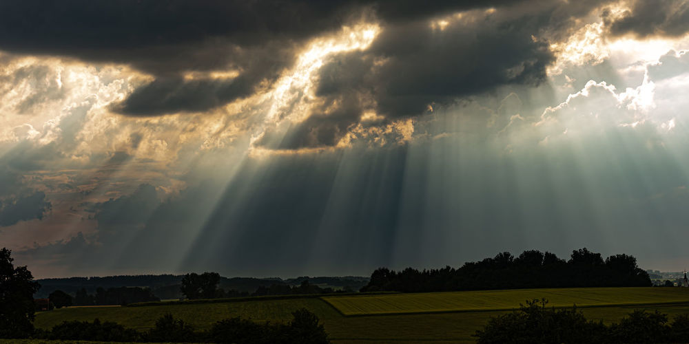 Sunlight streaming through storm clouds over land