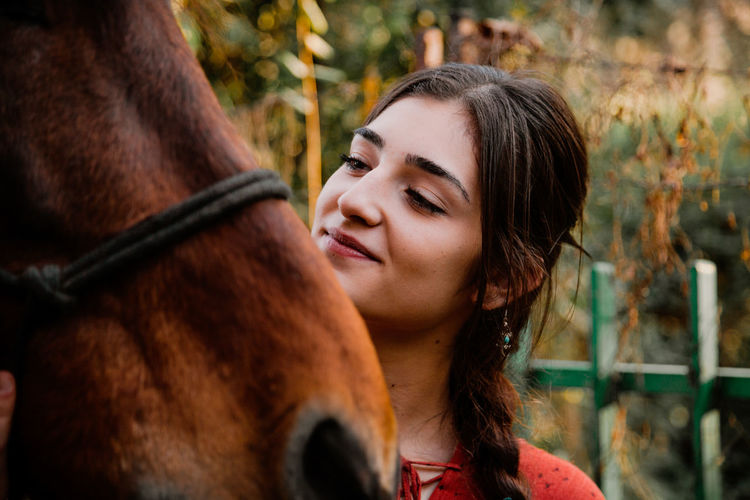 Close-up of young woman standing with horse outdoors