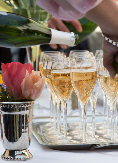 Cropped image of man pouring champagne in glasses on table