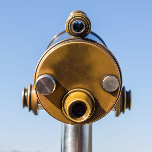 Low angle view of coin-operated binoculars against sky