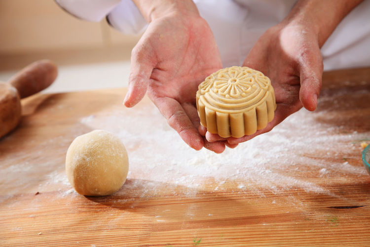 Midsection of woman preparing sweet baking food with dough at kitchen counter