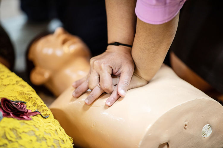 Midsection of woman giving cpr to mannequin 
