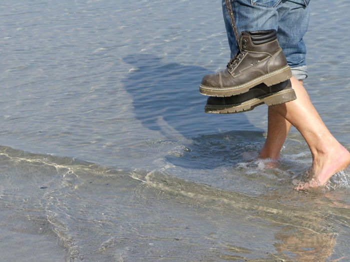 Low section view of man walking in water on beach