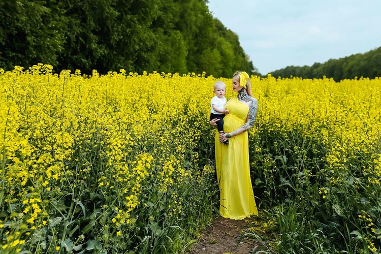 Pregnant woman with daughter standing by plants
