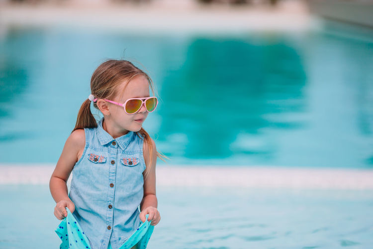 Cute girl wearing sunglasses against swimming pool