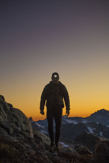 Portrait of backpacker wearing headlamp standing on mountain ridge.