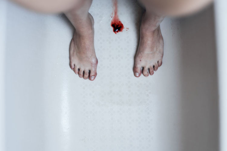 Directly above shot of blood amidst woman standing in bathtub