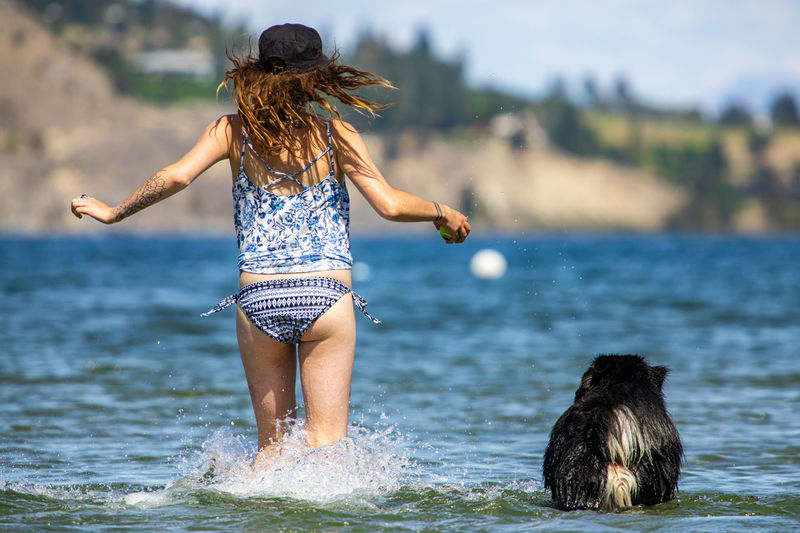 Rear view of woman with dog running in water
