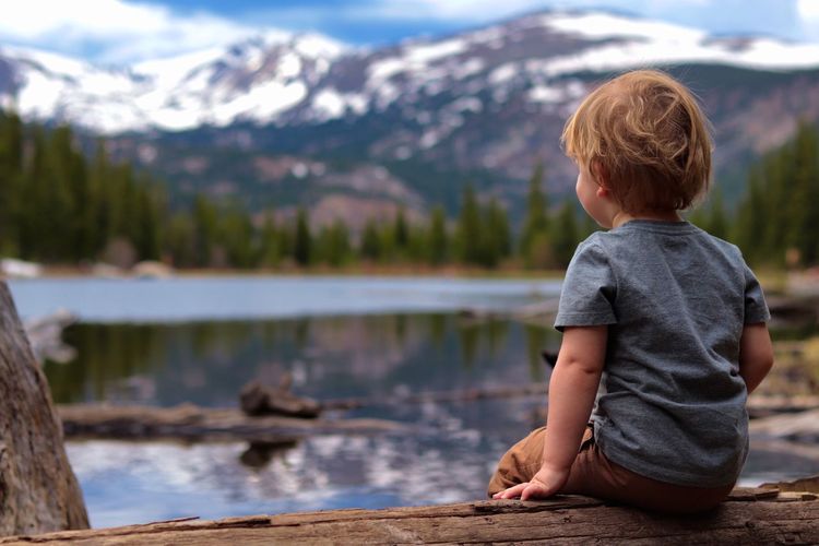 Boy looking at lake against mountain range