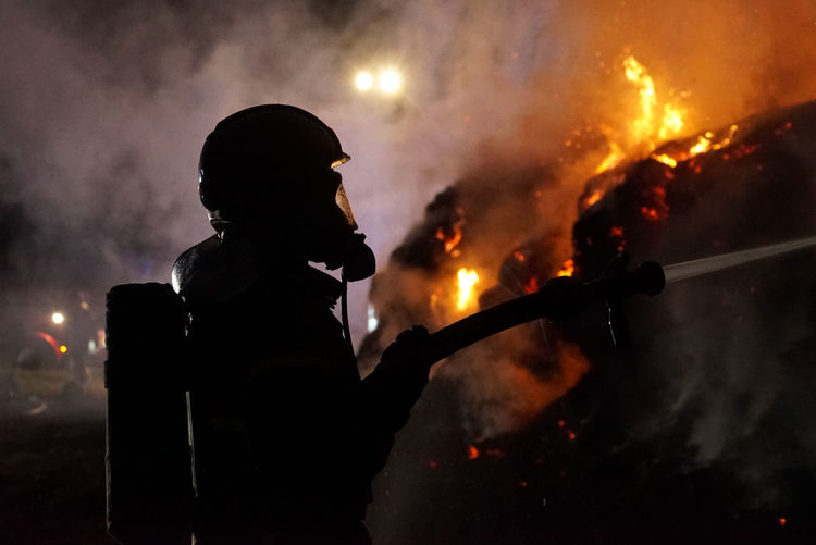 Side view of man holding fire at night