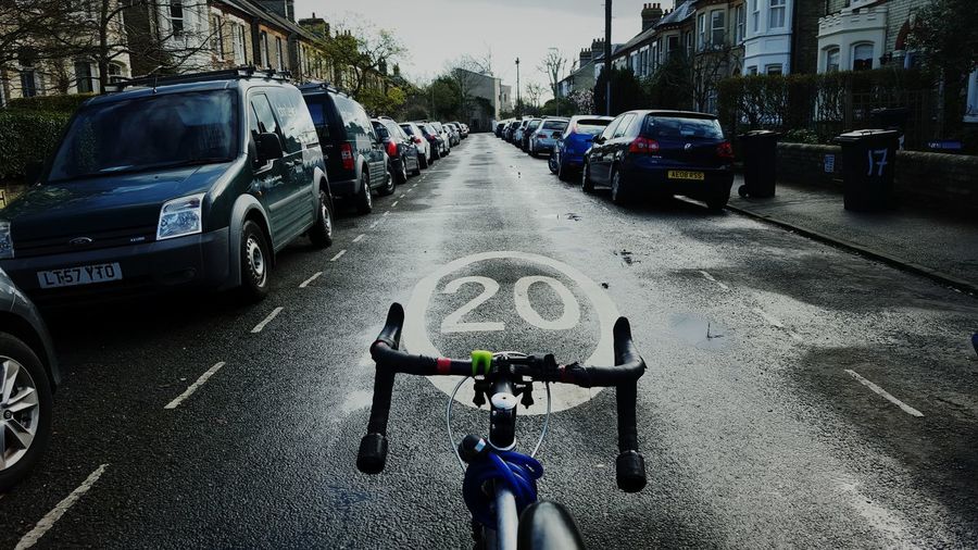 Cropped image of bicycle on road amidst cars in city