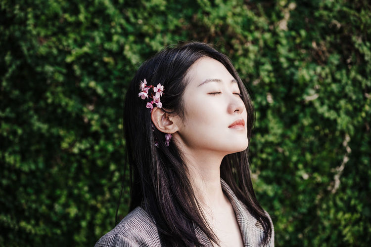 Portrait of beautiful chinese asian woman with eyes closed and almond tree flowers.spring time,relax