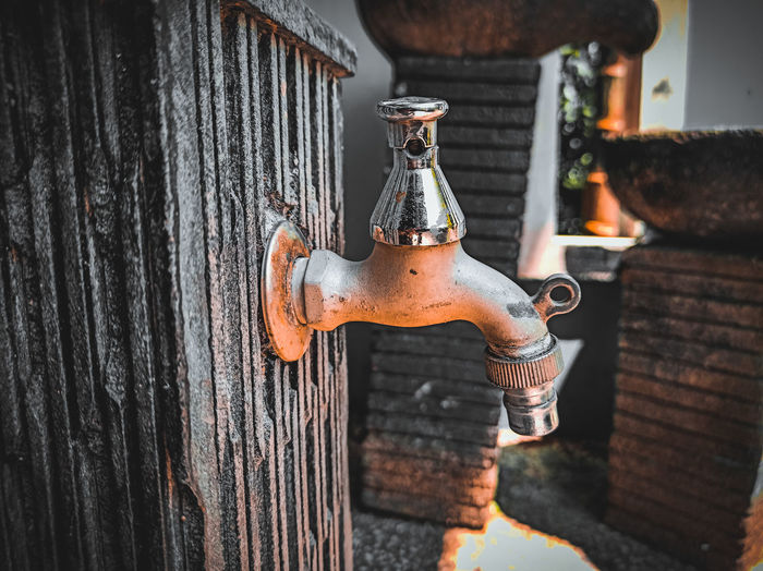 Close-up of old faucet against wall