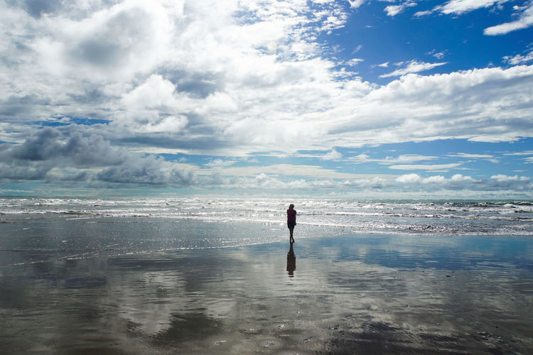 Woman walking at beach against sky