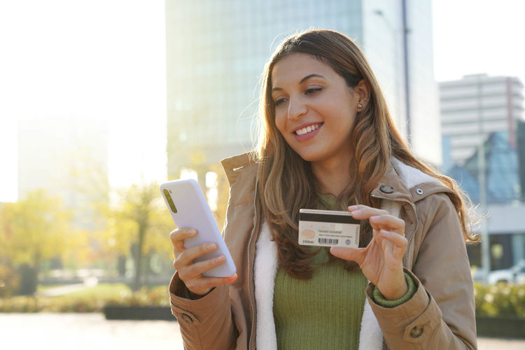 Woman typing number of credit card on smartphone makes purchase online or checks bank account 