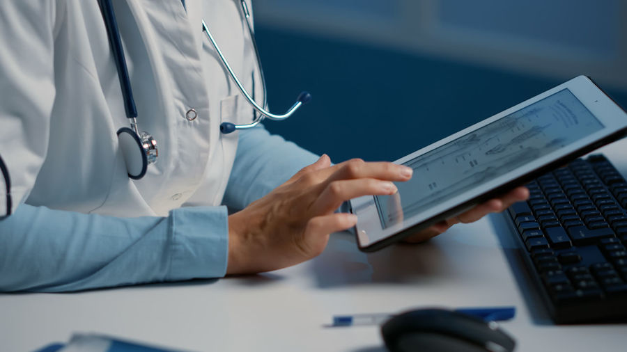 Midsection of doctor using digital tablet