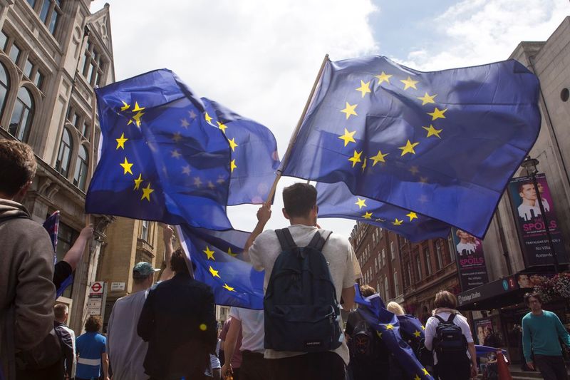 Low angle view of people with european union flags walking on city street