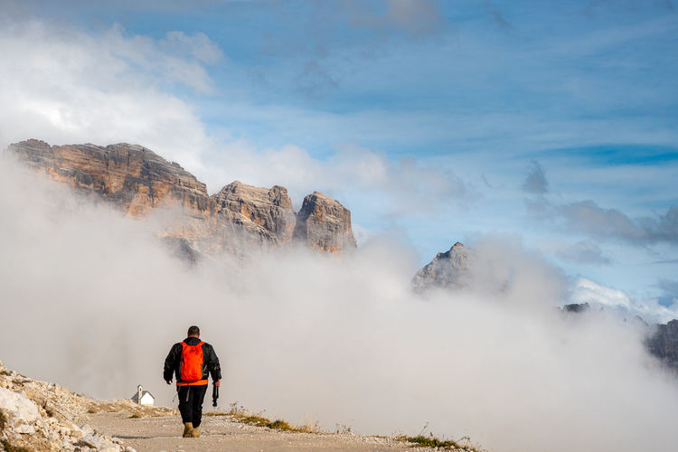Rear view of man standing on mountain against sky