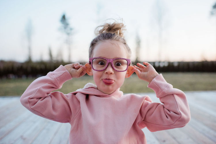 Portrait of a young girl pulling silly faces with pink sparkly glasses