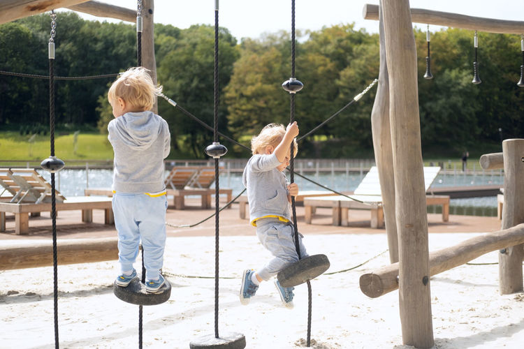 Rear view of children playing on swing at playground